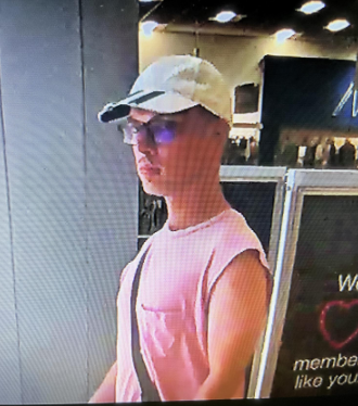 white, 5'6" tall, average build, wearing glasses, a white hat, sleeveless shirt, shorts and a crossbody bag
