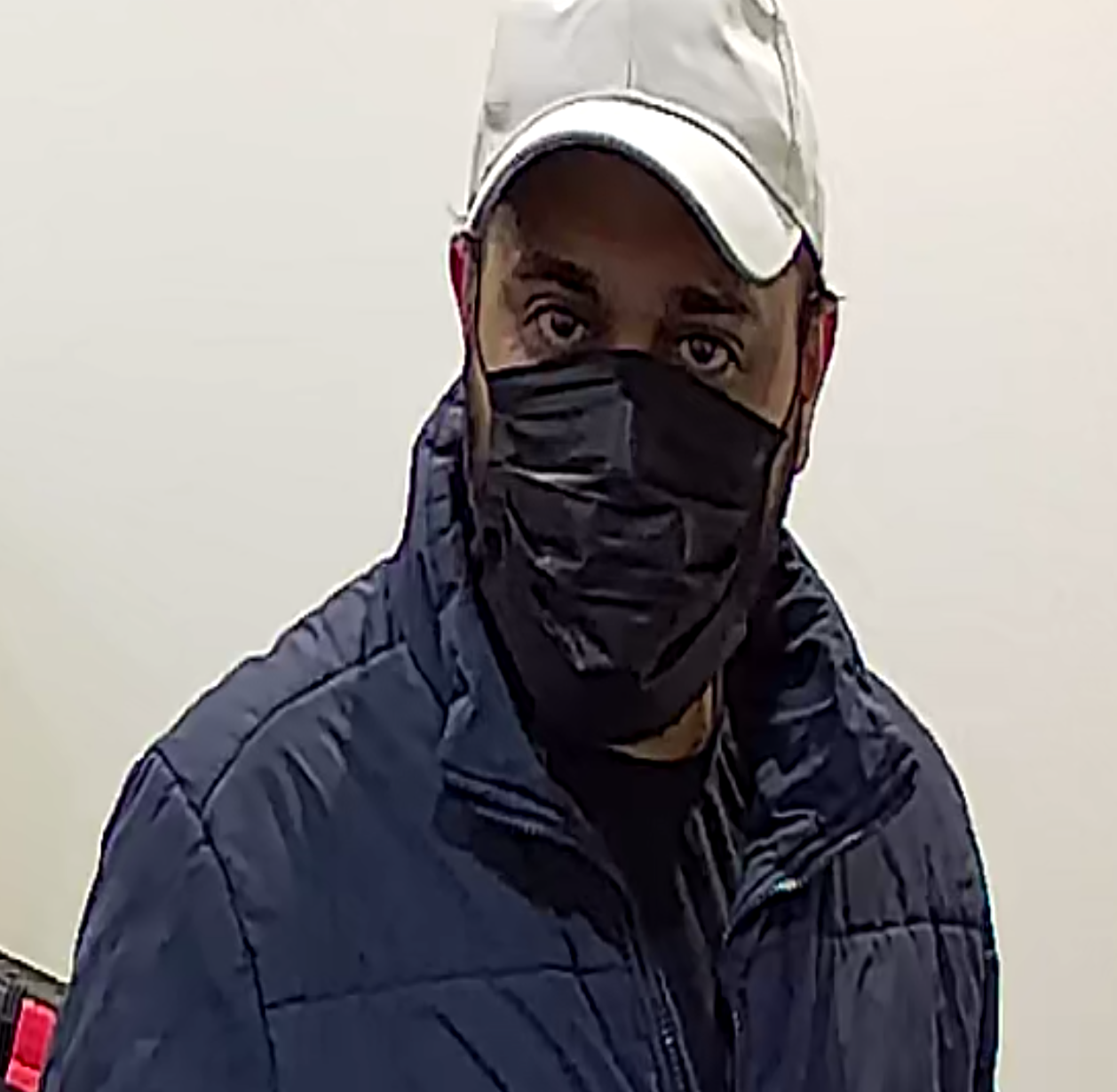 Brown male, black mask, white ball cap, blue jacket